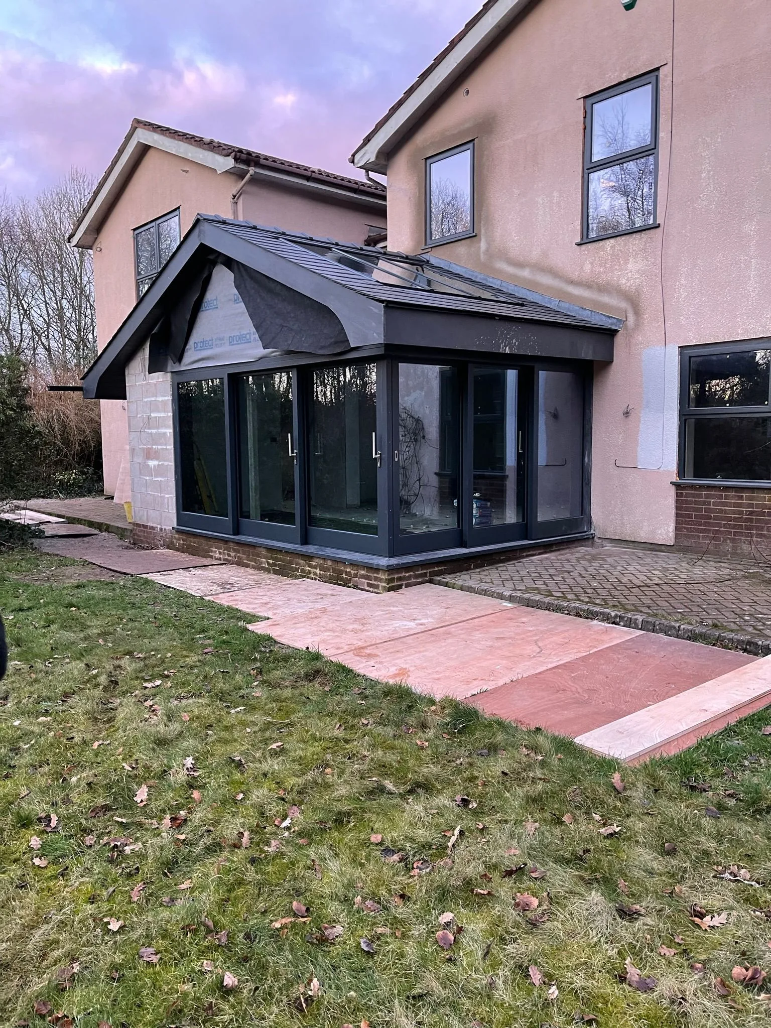 Anthracite-painted timber orangery with steep gable roof on a rendered Lancashire home