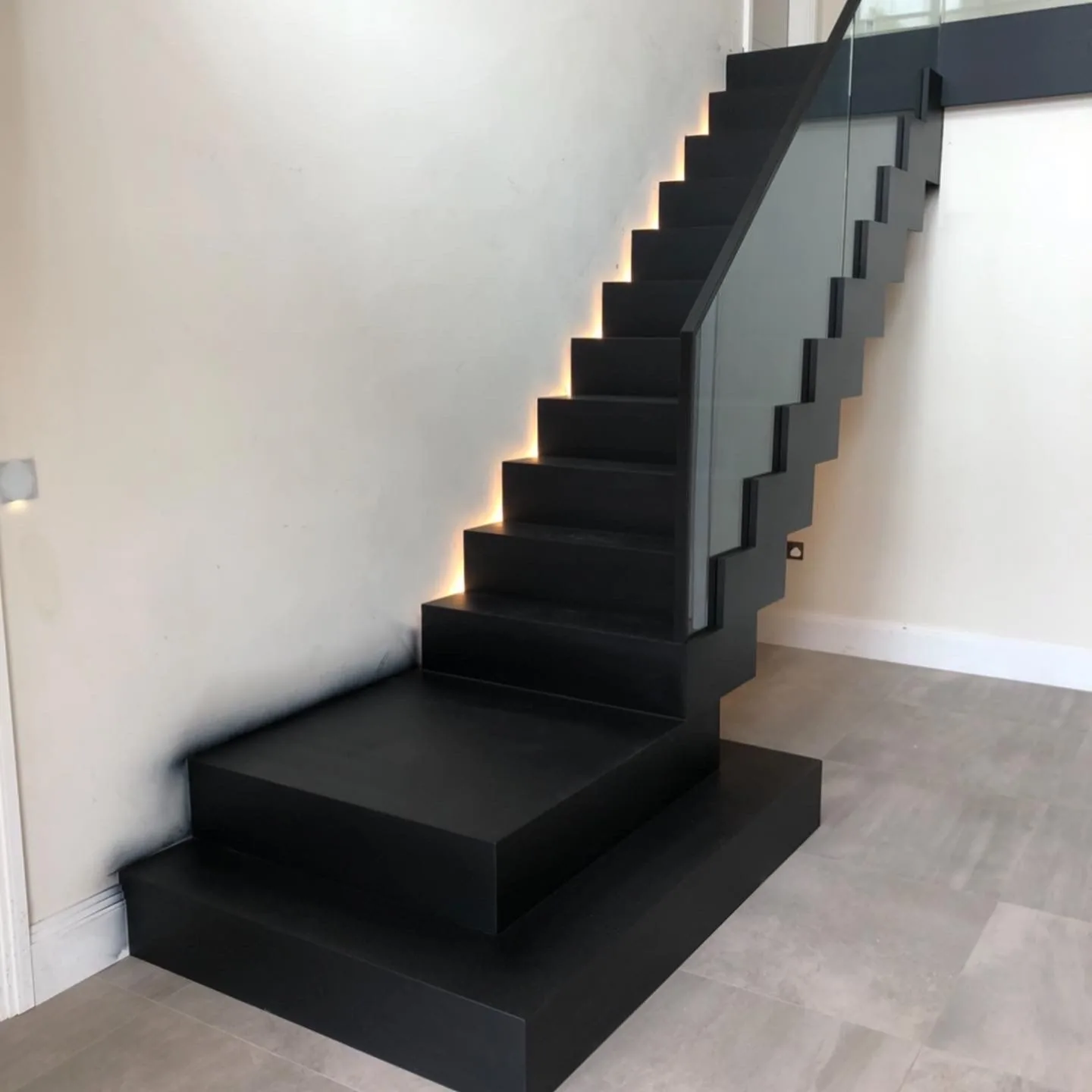 Floating black-stained oak staircase with concealed LED step lighting and glass balustrade