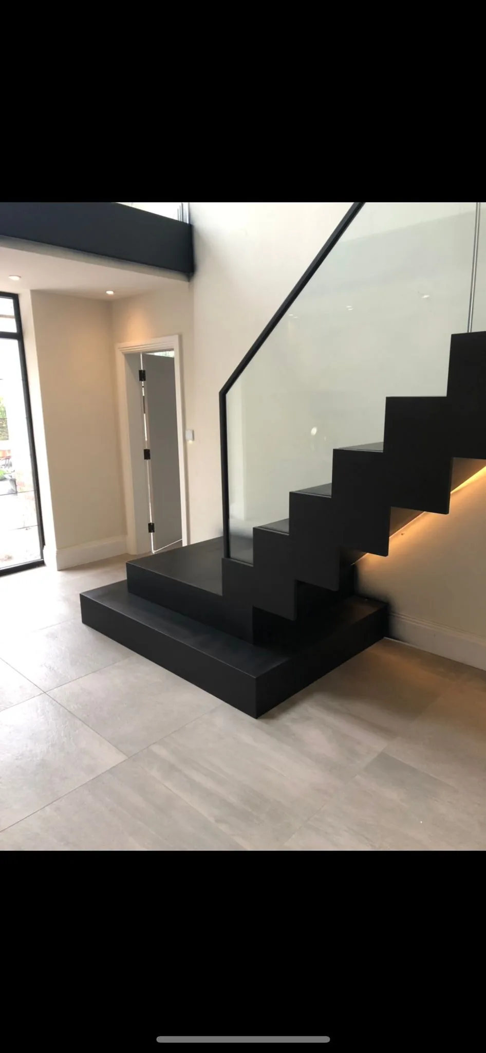 Bespoke matt-black zigzag staircase with frameless glass balustrade and concealed LED