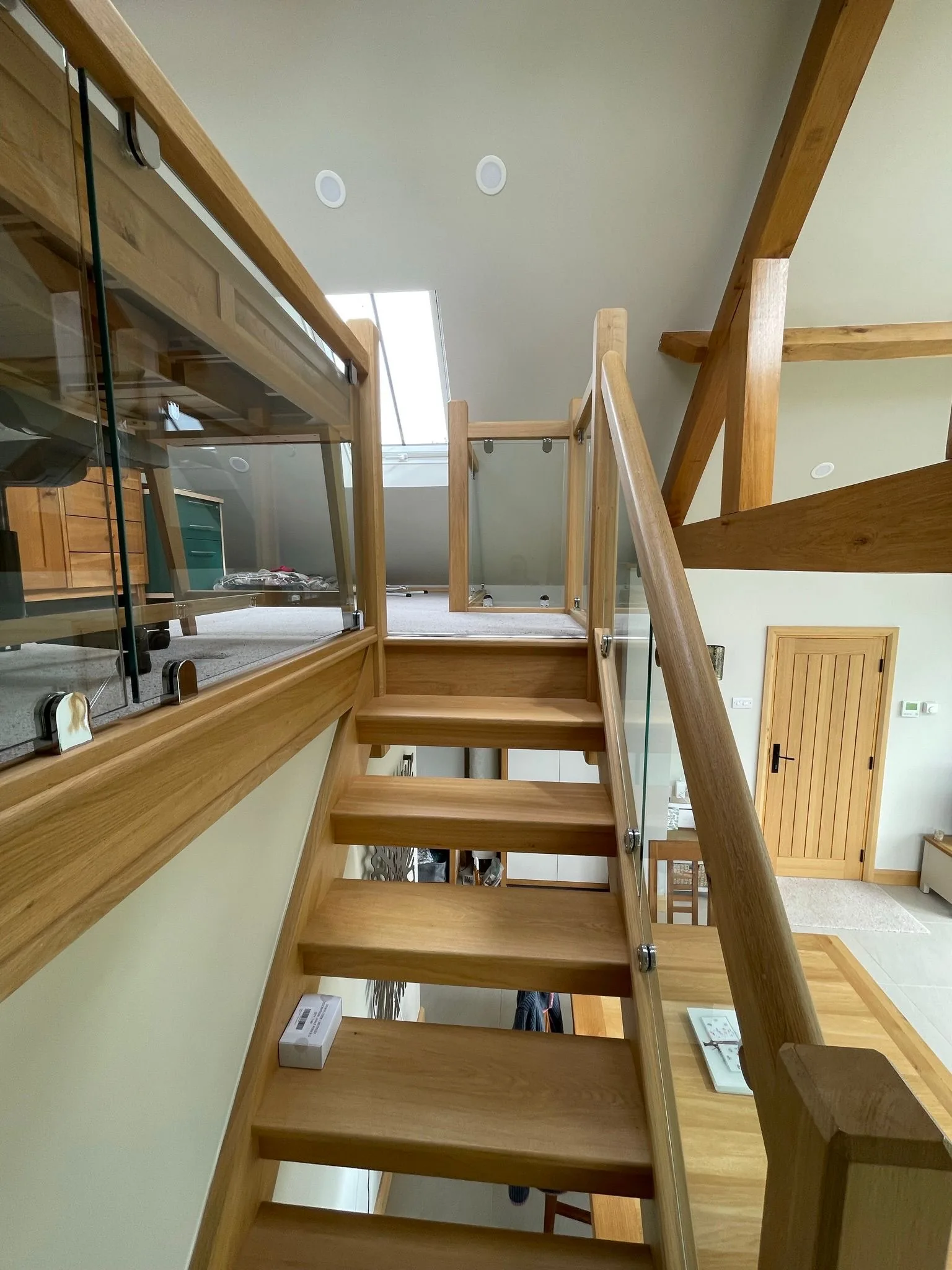 Bespoke floating oak staircase with frameless glass balustrade beneath a roof lantern