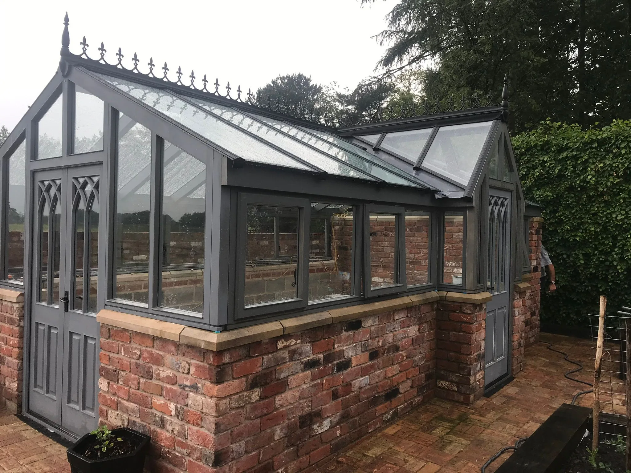Bespoke Gothic-style timber glasshouse with ornamental iron roof cresting