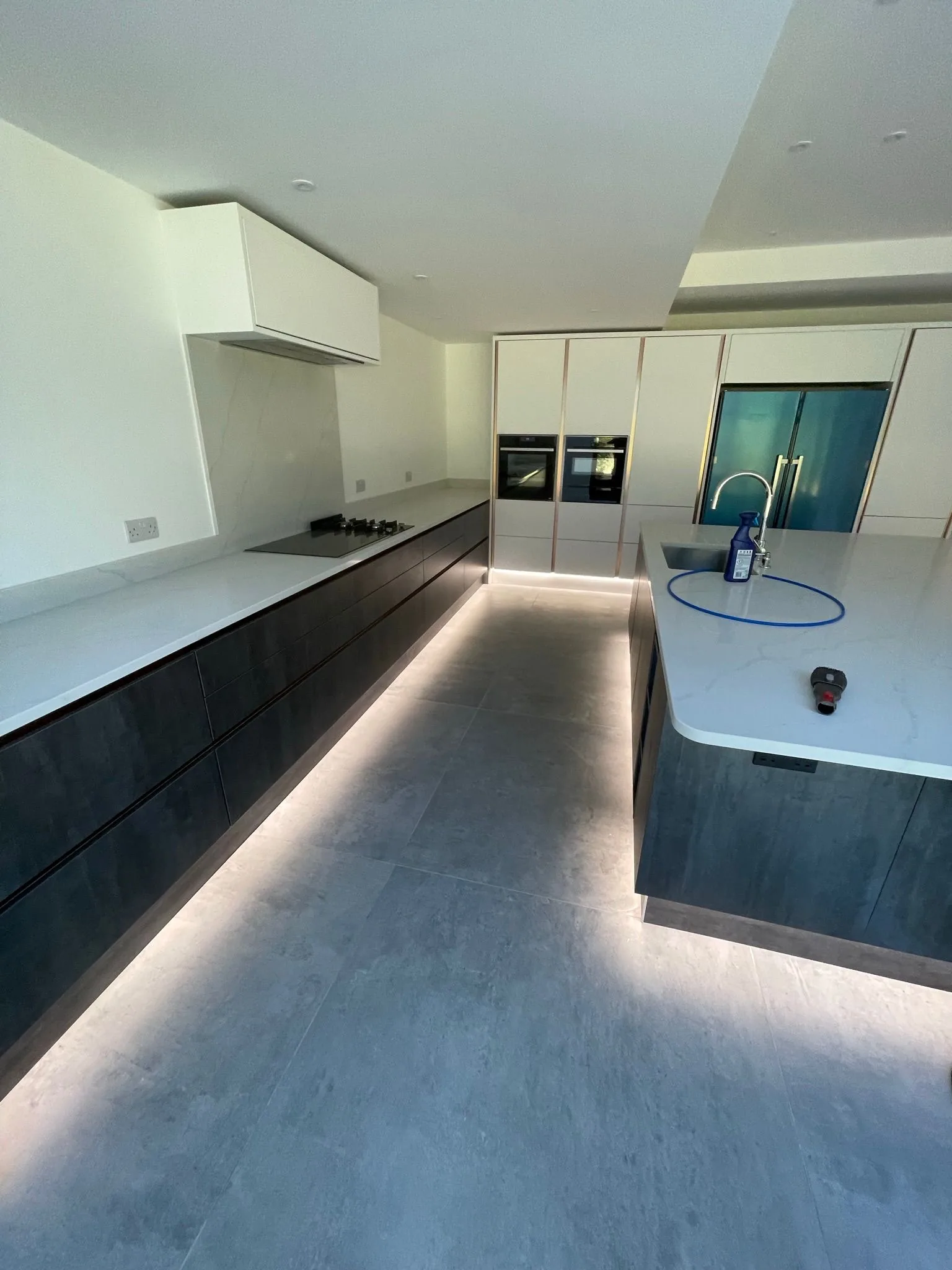 Contemporary handleless kitchen with marble worktop and concealed LED plinth lighting