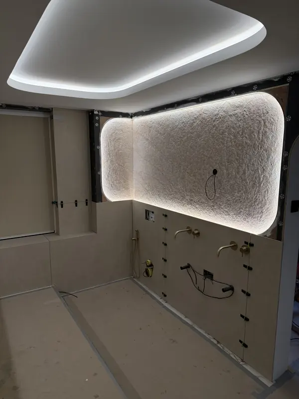 Backlit textured stone panel with a rounded outline on the en-suite mirror wall