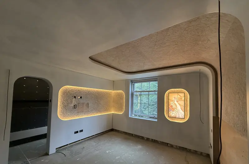 Master bedroom with a curved coffered ceiling, backlit textured wall panels and an arched doorway