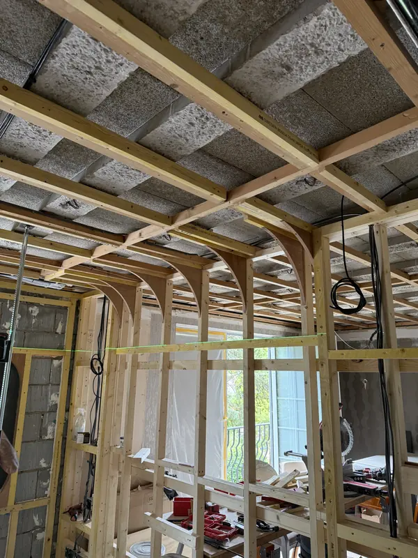 A row of curved plywood ribs forming the edge of a new ceiling