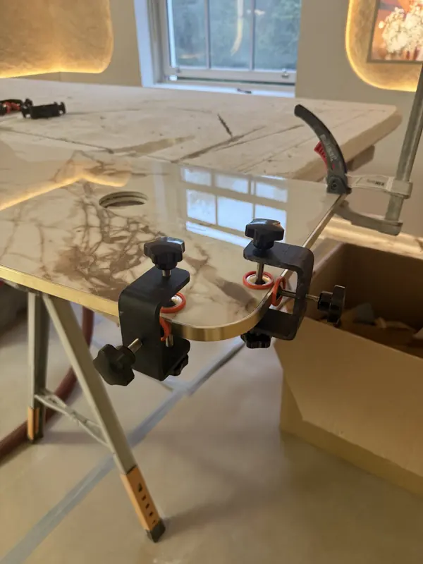 Marble-effect vanity top mitred and held in clamps while the joint sets
