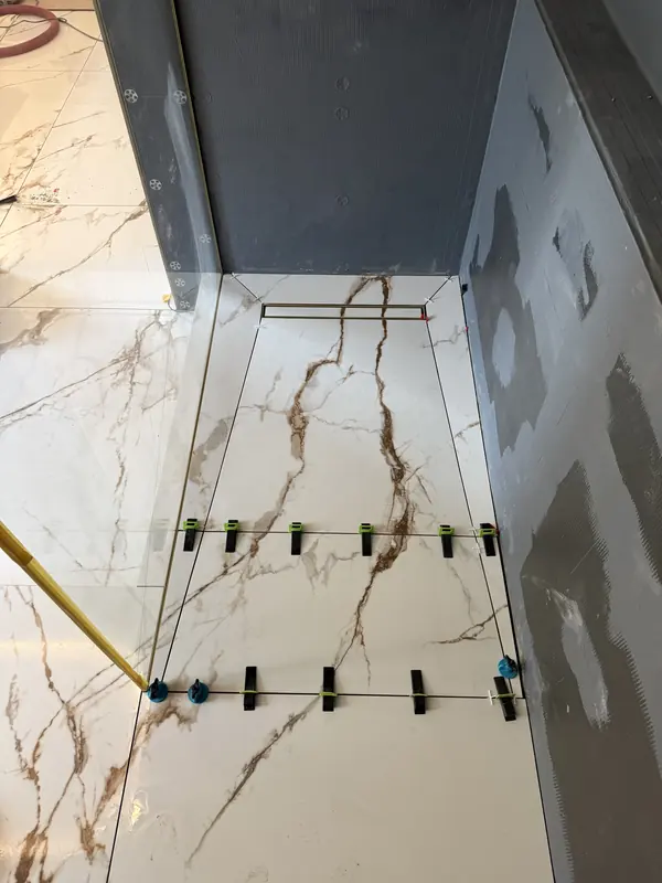 Large-format shower floor tiles with levelling clips and a linear drain