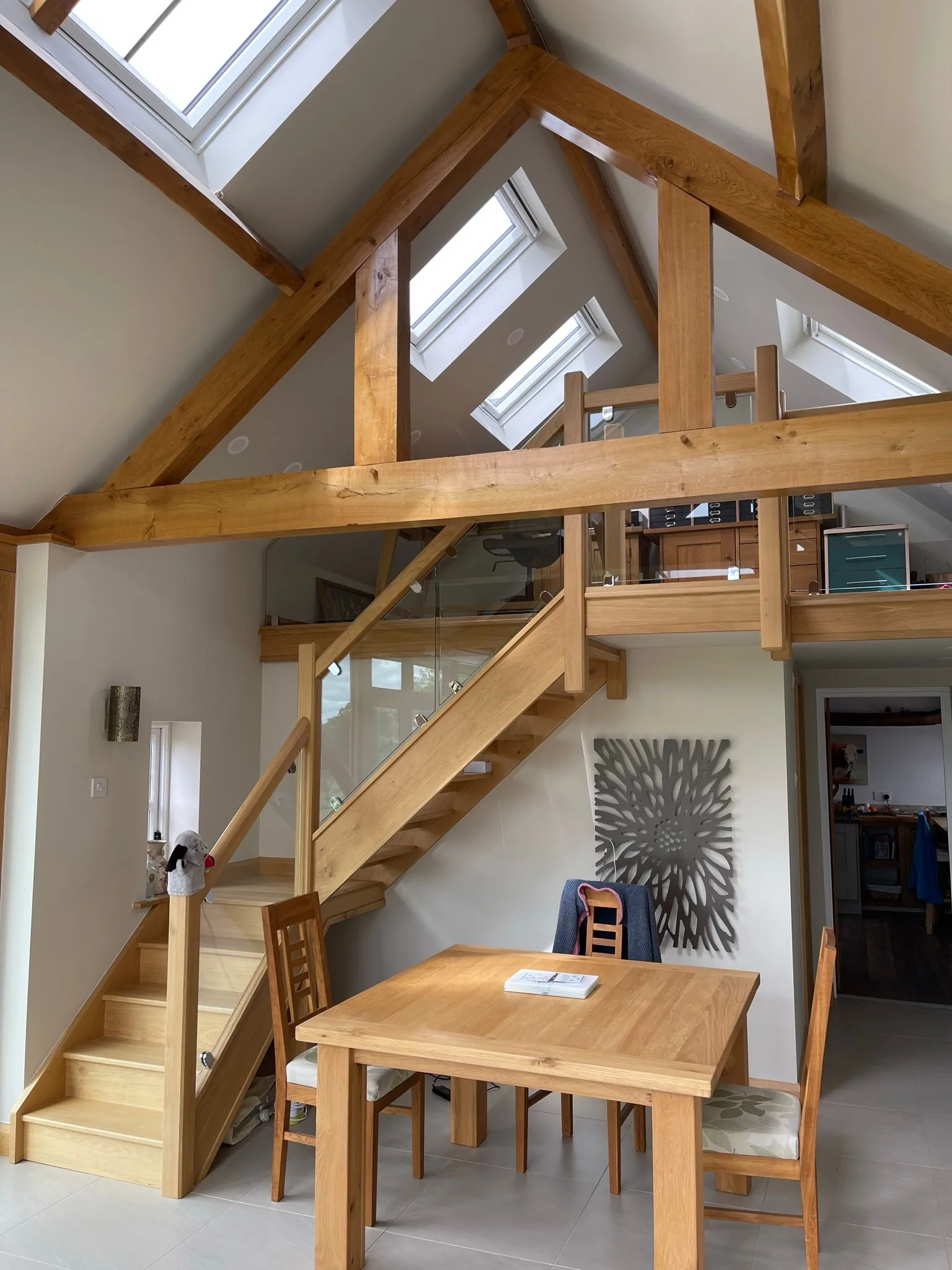 Oak post-and-beam frame interior with vaulted ceiling and mezzanine dining level overlooking the living space