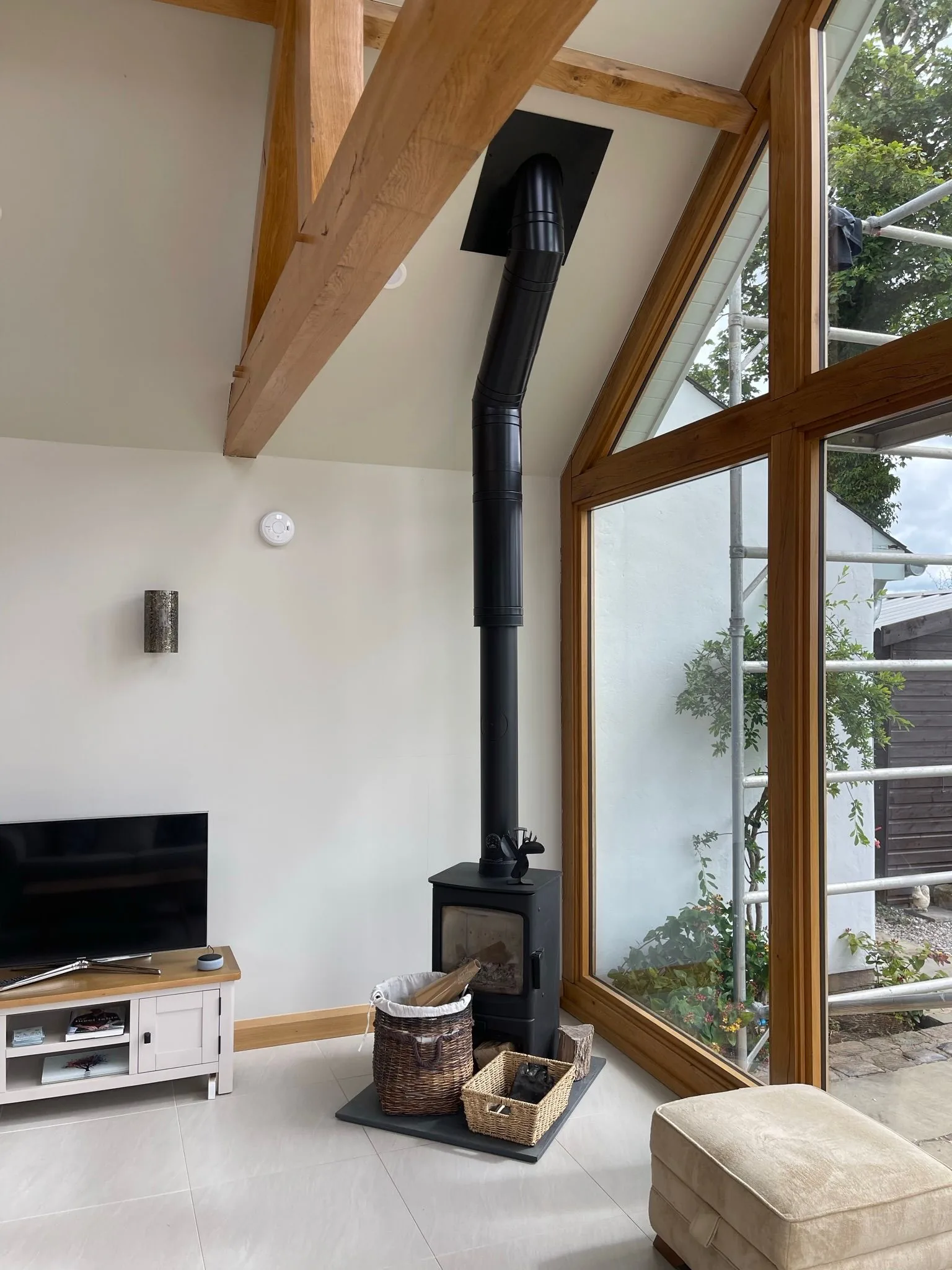 Oak-framed snug with exposed structural post, fitted shelving and a wood-burning stove set into the chimneybreast