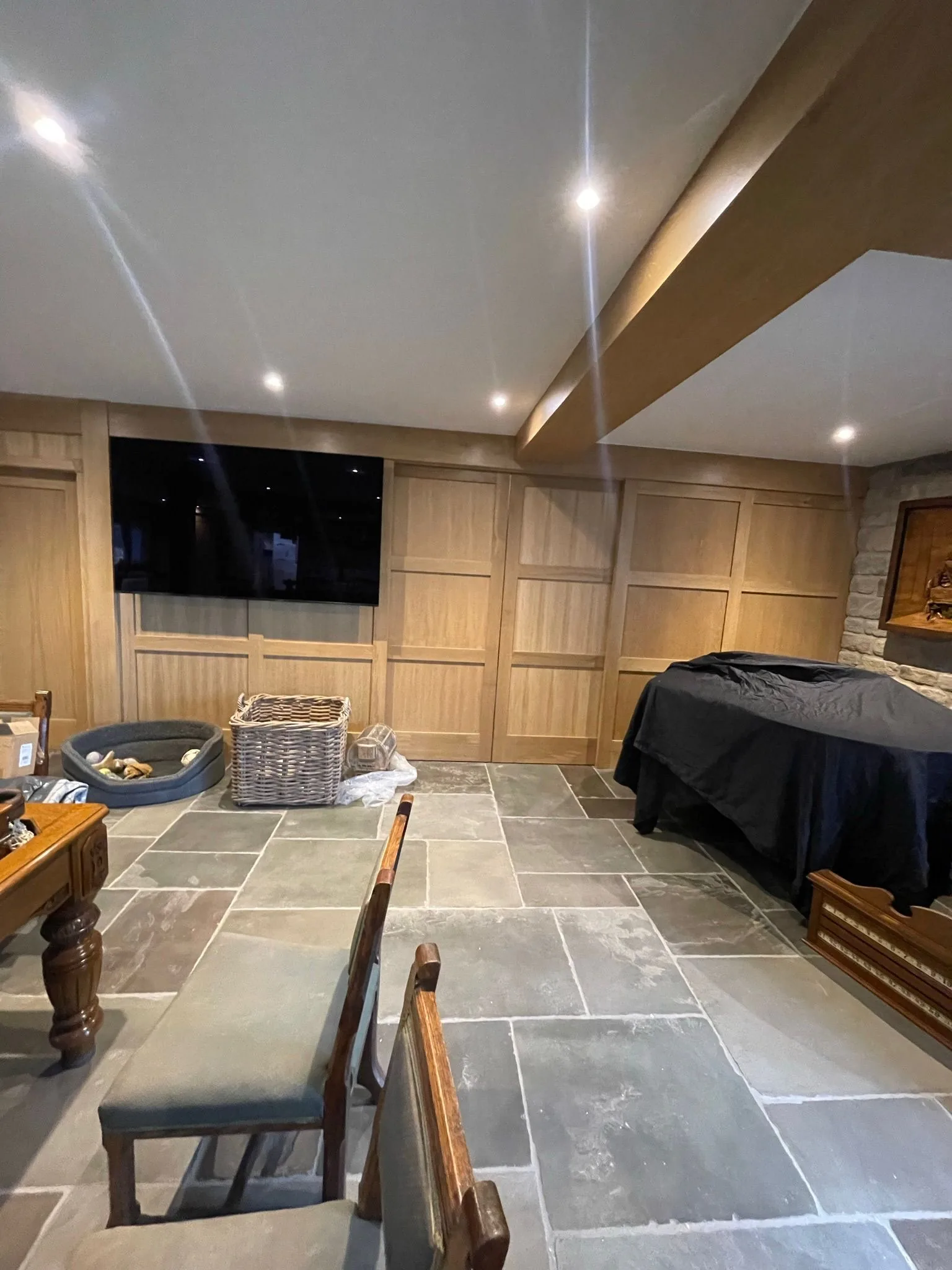 Bespoke oak wall panelling with concealed sliding doors and flagstone floor