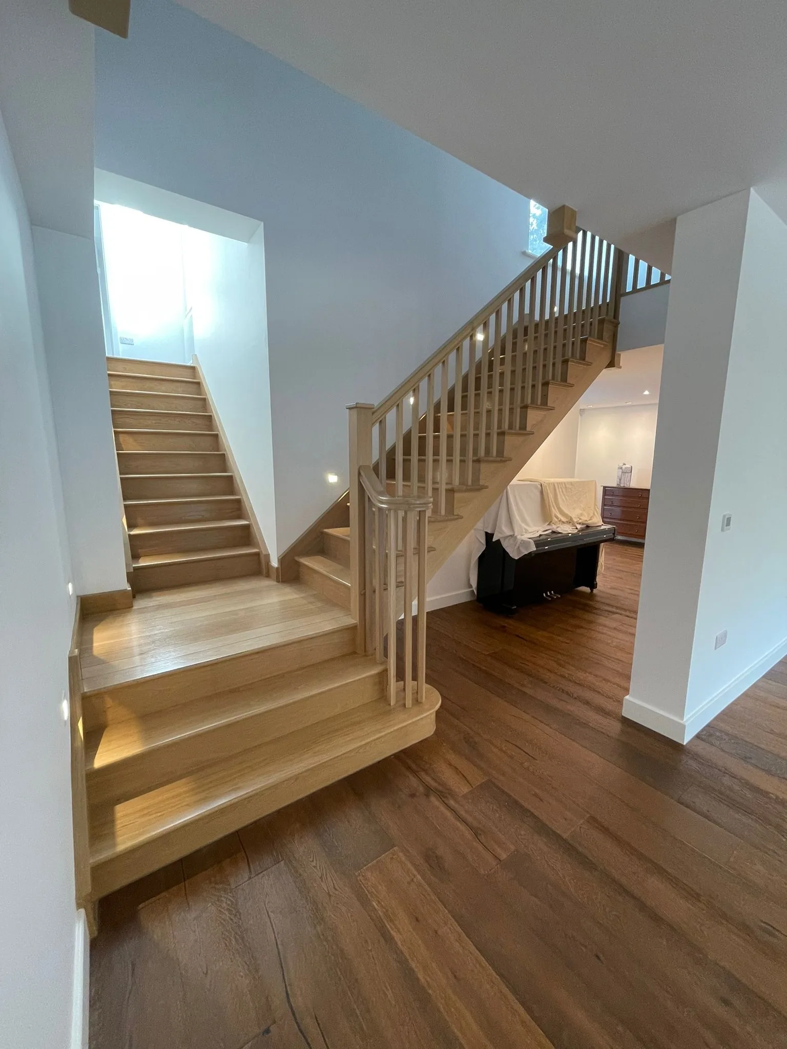 Solid oak staircase with elliptically curved treads and white-painted spindles