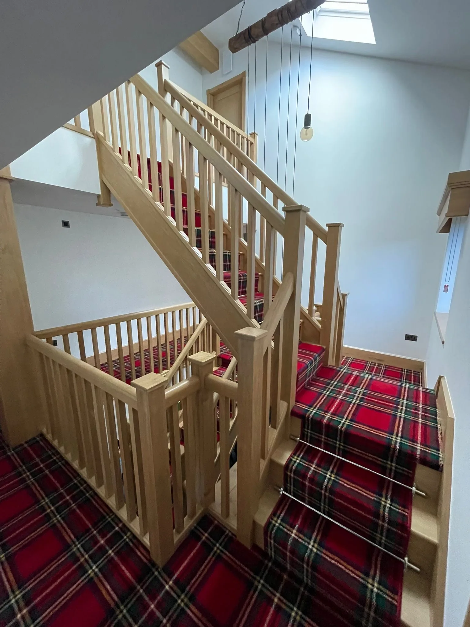 Bespoke oak staircase with red tartan stair runner viewed from the landing