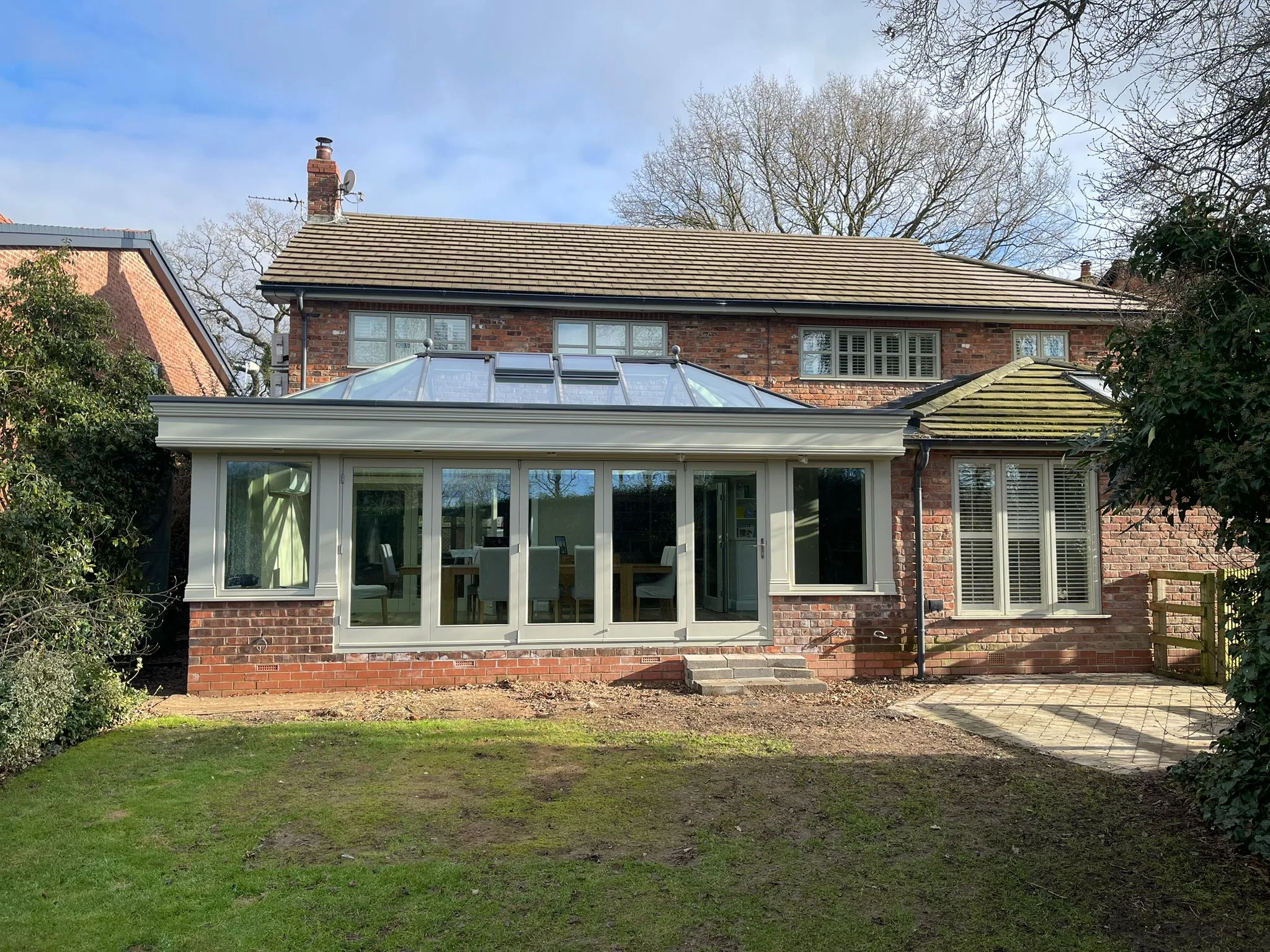 Rear elevation of a white-painted timber orangery with sash windows and a lead-effect roof lantern