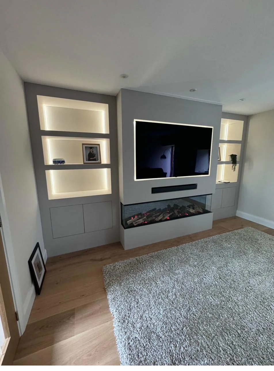 Bespoke painted media wall with integrated fireplace and illuminated display alcoves by Joinery Limited
