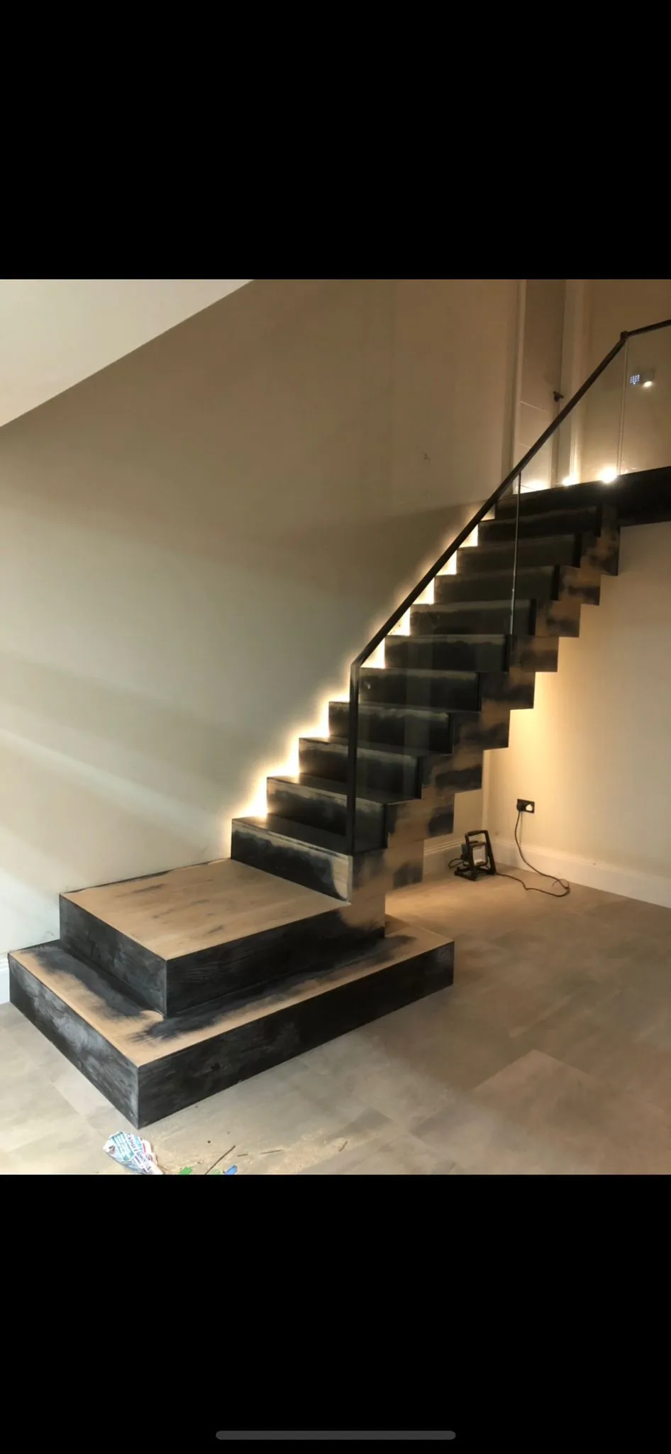 Scorched-finish timber open-tread staircase with frameless glass balustrade and steel string